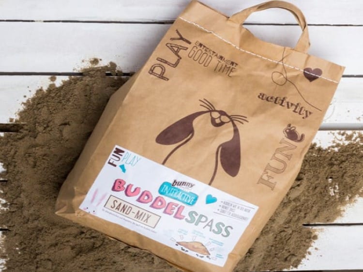 Bunny Buddelspass sand-mix til gnavere, ideel til leg og aktivitet, præsenteret i en papirpose med illustrationer af en kanin.