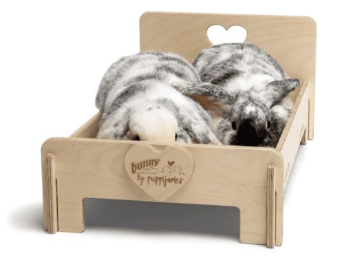 To flotte kaniner hviler i en træ-bunke fra Bunny by Puppijames, designet til gnavere og mindre kæledyr, som giver komfort og hygge.