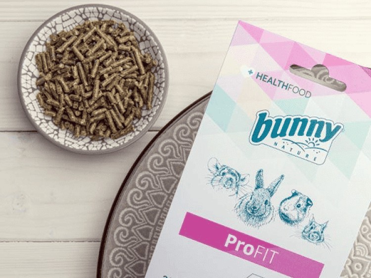 Bunny Nature ProFIT foder til gnavere, pakket i en farverig pose med illustrationer af forskellige kæledyr. Foderet er i form af små pinde, præsenteret i en skål. Ideelt til kaniner og andre mindre kæledyr for optimal sundhed.